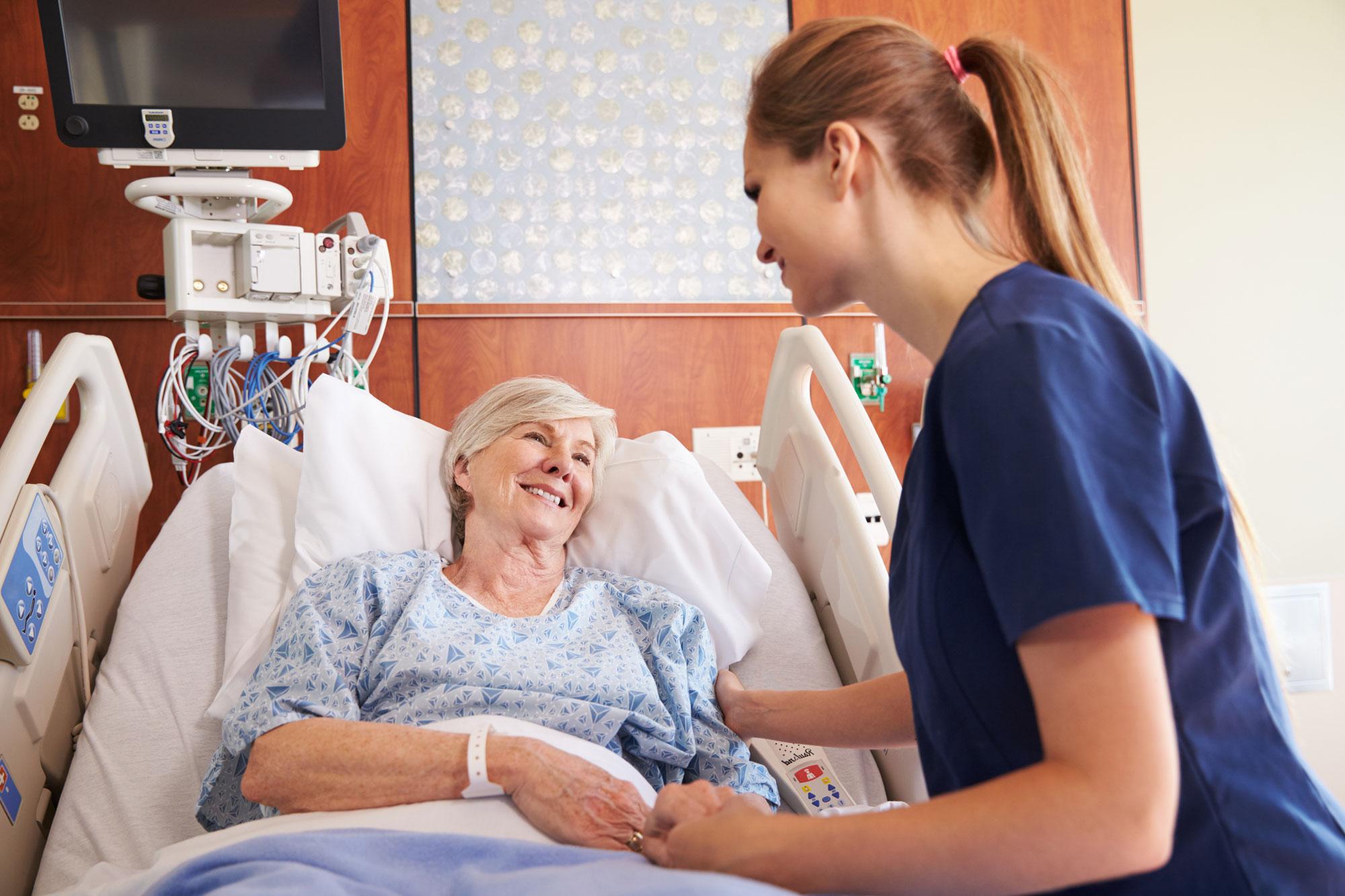 A female nurse is tending to an elderly patient